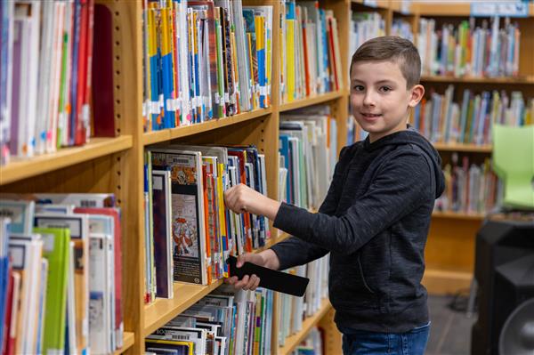 boy smiling while getting book off shelf